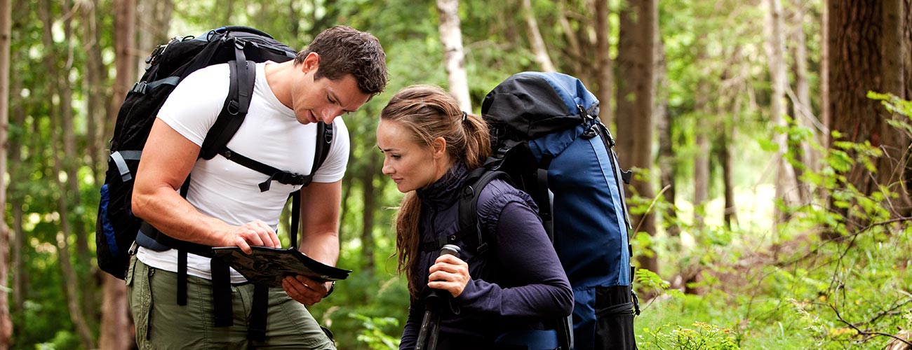 Paar mit Rucksack beim Betrachten einer Wanderkarte mitten im Wald