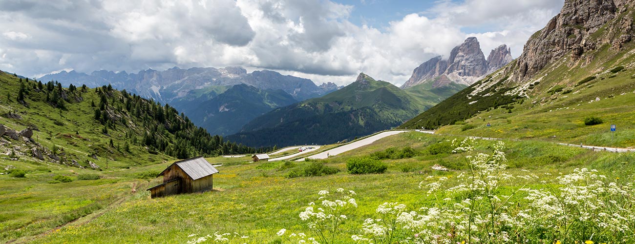 Panorama of Val di Fassa with pastures and low clouds