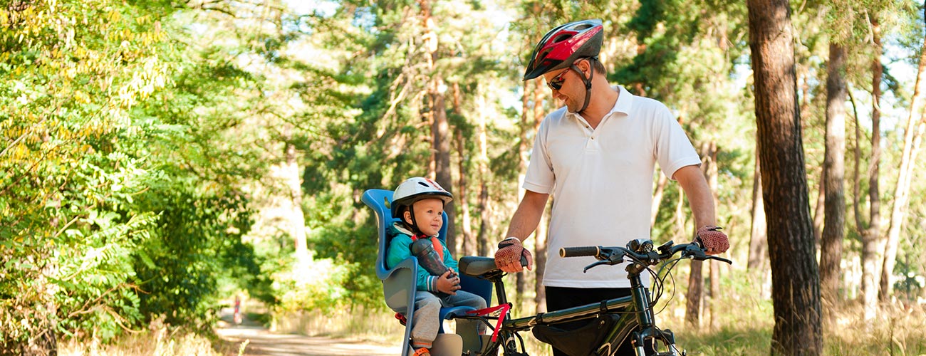 Papà in bicicletta con bambino nel seggiolino