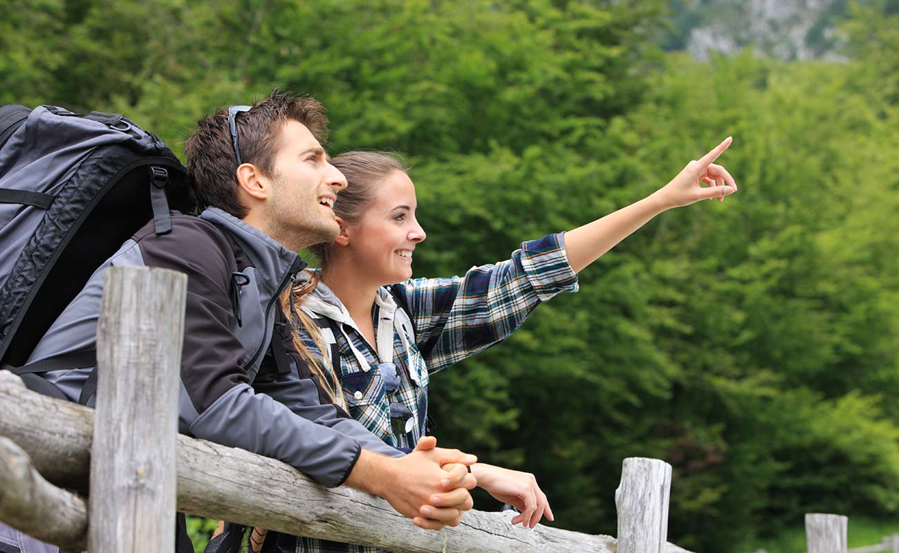 A couple during an excursion on a wooden fence looks into the distance