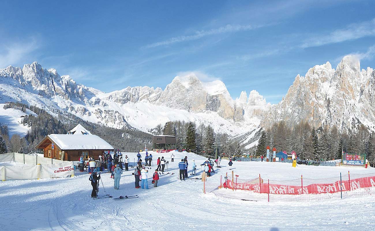 Skiers  in the ski area around Vigo di Fassa, surrounded by mountains full of snow